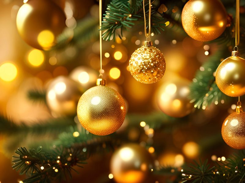 Close up of golden balls on christmas tree. Bokeh garlands in the background. New Year concept.